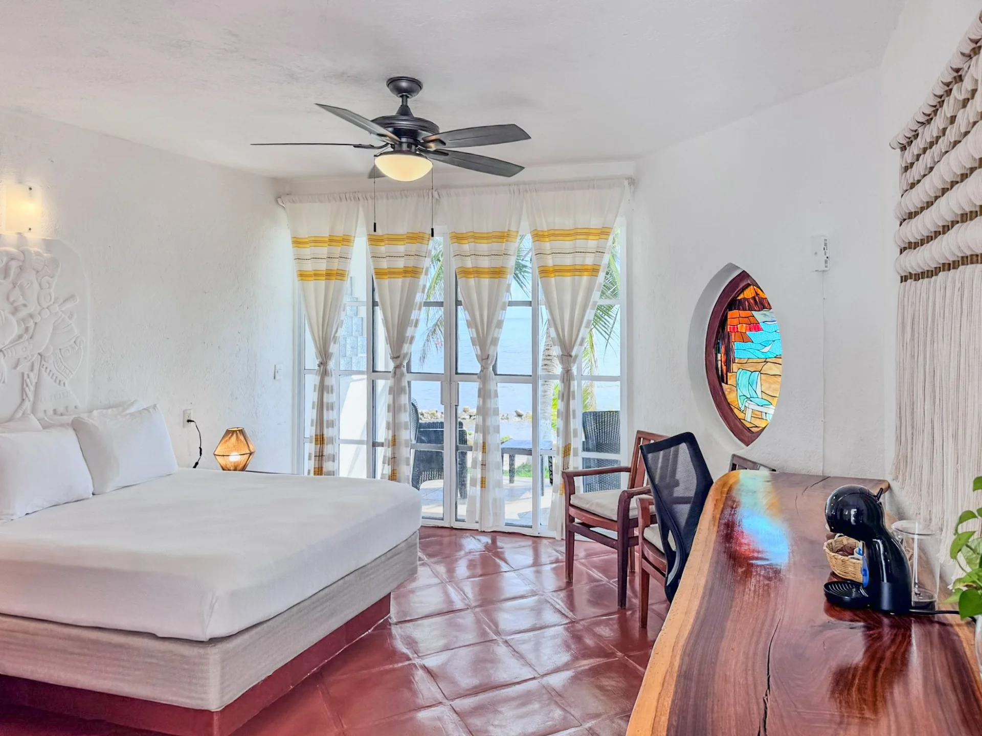 Recámara con ventana de vitral y vista al mar en villa Casa Cenote, Bahía Tankah Tulum
