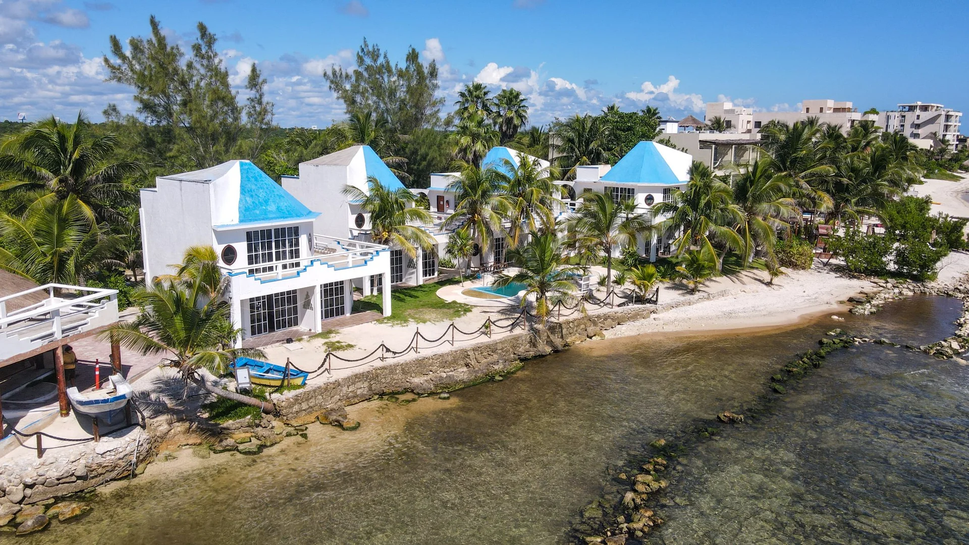Vista aérea de las villas con techado azul y acceso directo a la playa en Casa Cenote Tankah