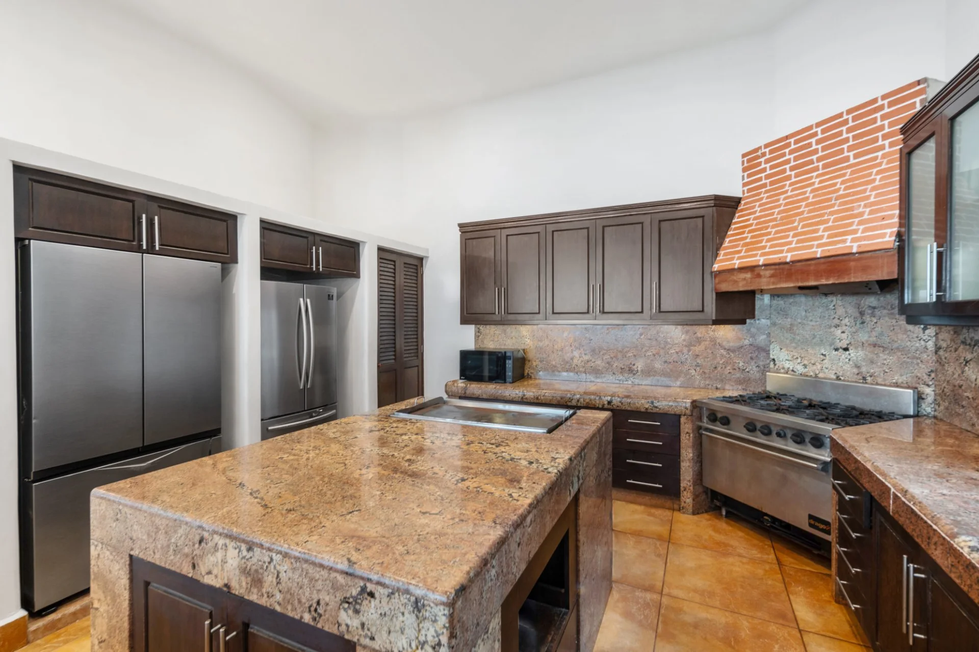 Equipped kitchen with granite island and brick hood at Hacienda Caracol, Tulum