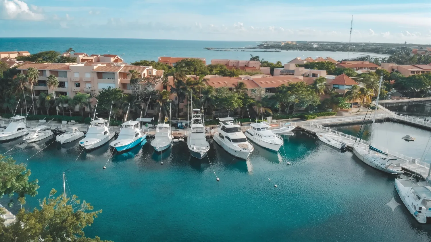 Puerto Aventuras marina — yachts docked at the slips with condos and palms, Riviera Maya
