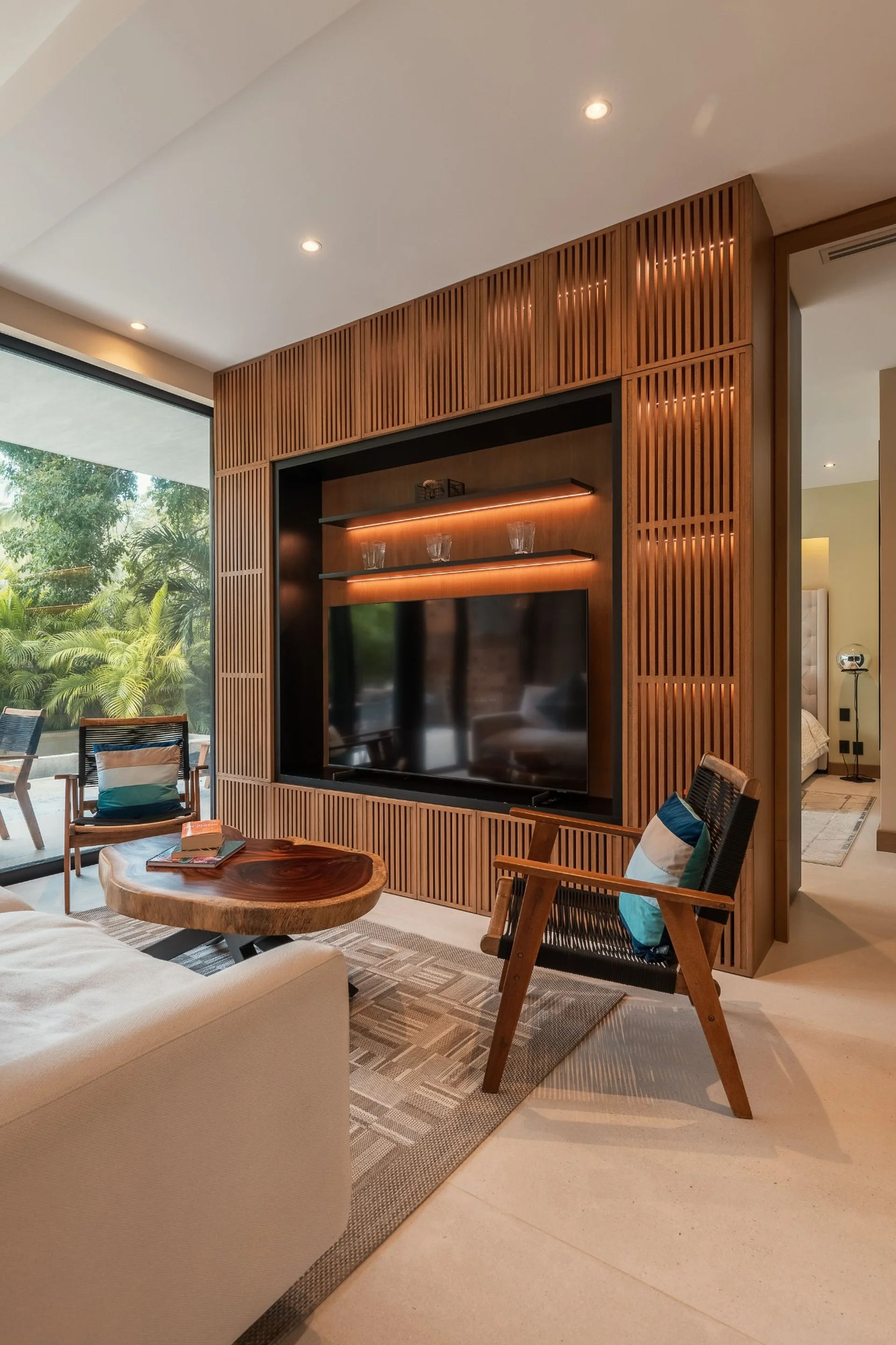 Sala con muro de madera y TV en departamento de lujo SOLEii, Riviera Maya