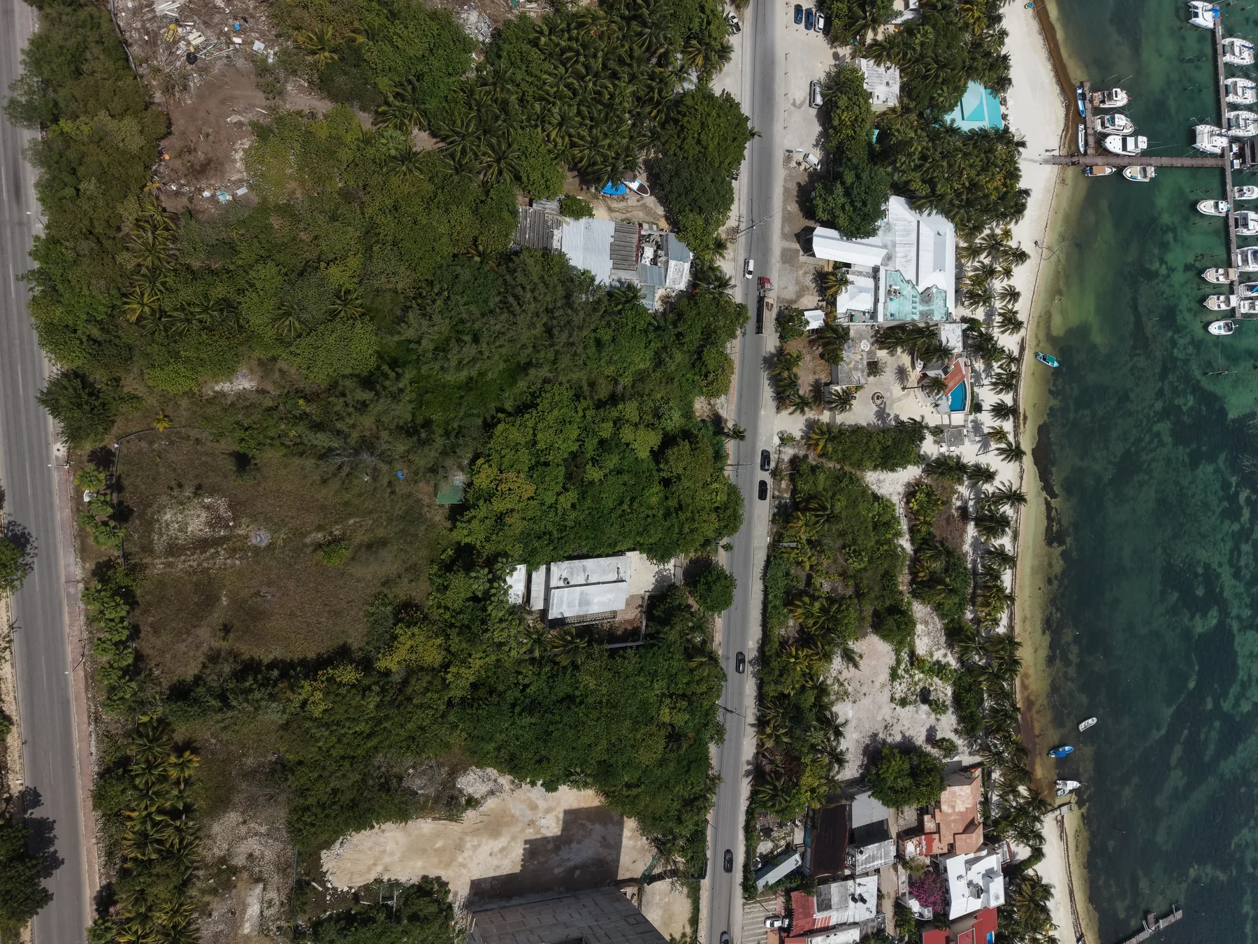 Frente de mar del predio en Costa Mujeres: playa, embarcaderos y la bahía de Mujeres — fotografía propia con dron
