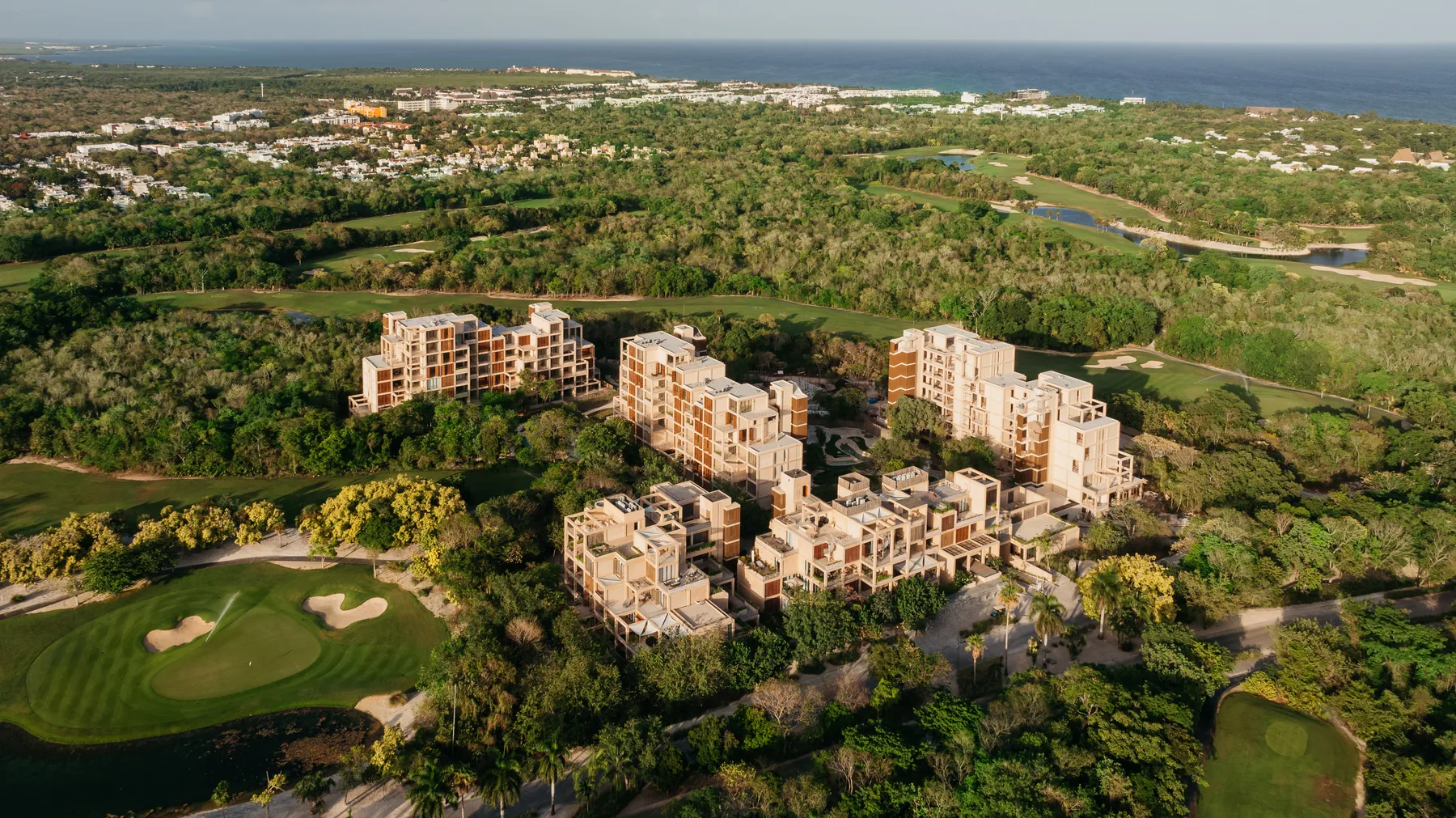 Vista aérea de The Village en el master plan de Corasol, con el campo de golf y el Caribe al fondo