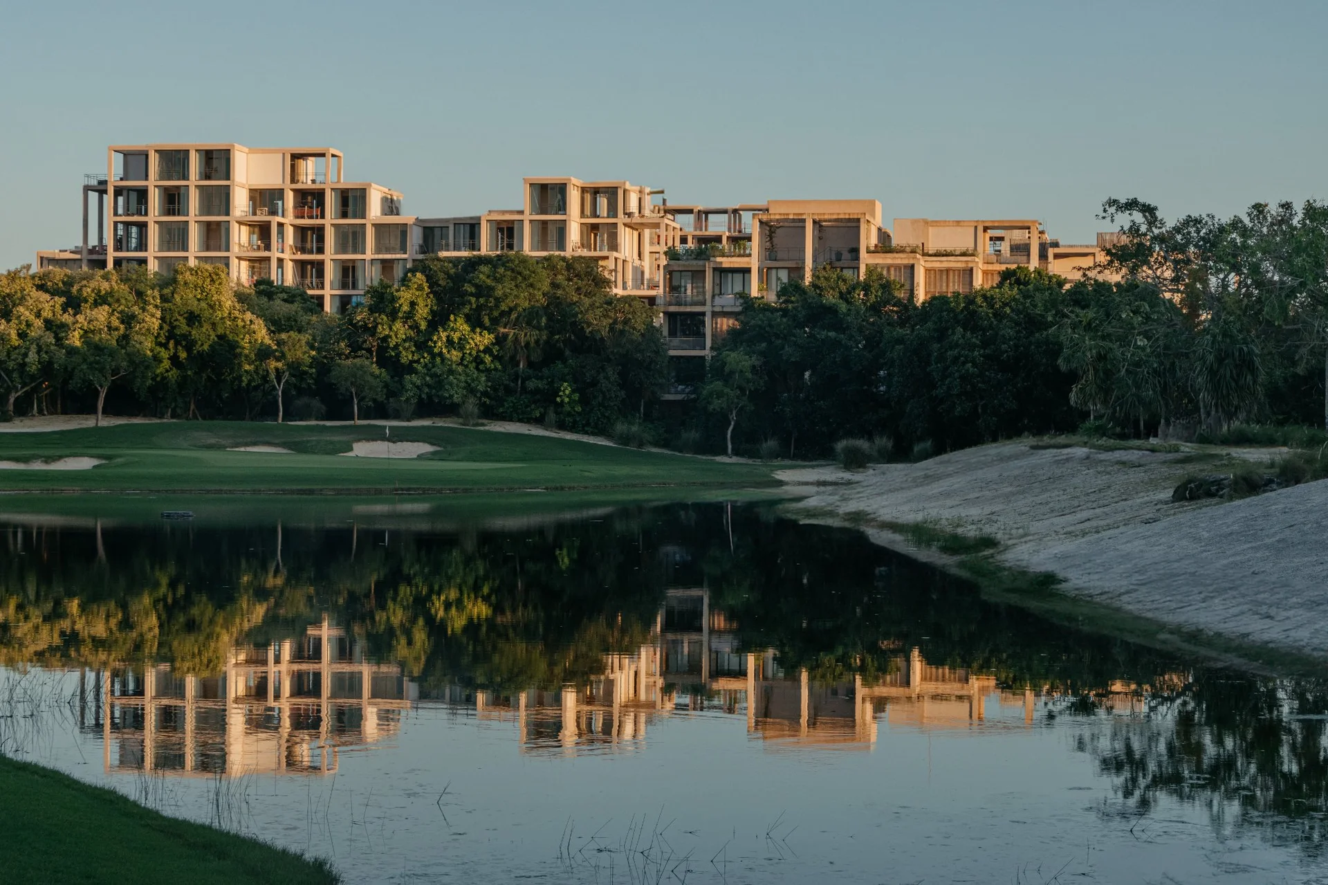 The Village Resort & Residences reflejado en la laguna al atardecer, Golf Gran Coyote, Corasol