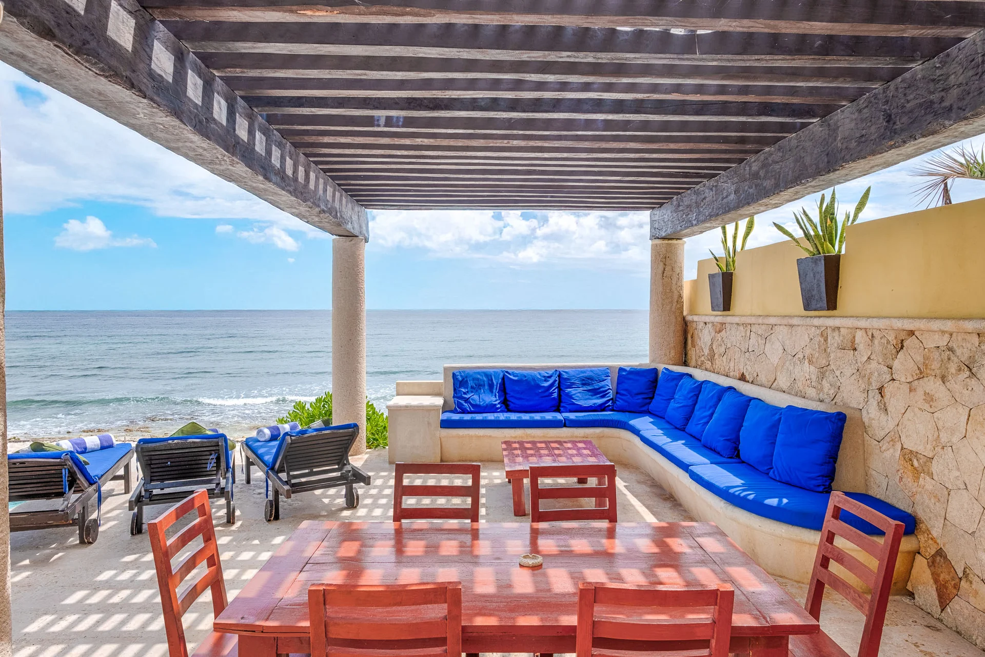Comedor exterior con sala azul frente a la playa en Villa Arghy Tulum