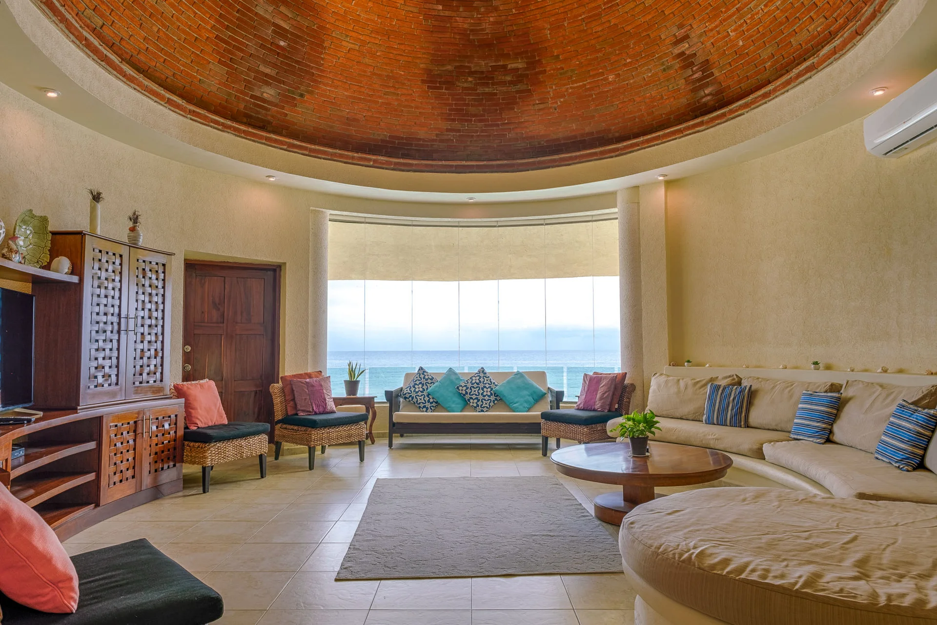 Sala principal con cúpula artesanal de ladrillo y vista al océano en Villa Arghy